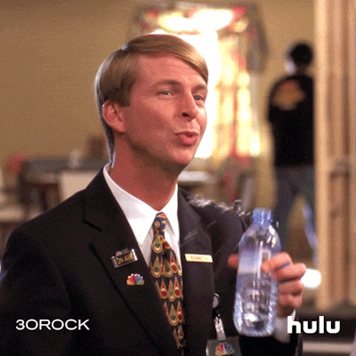 A man struggles to drink out of a bottle of water because his hand is shaking so hard