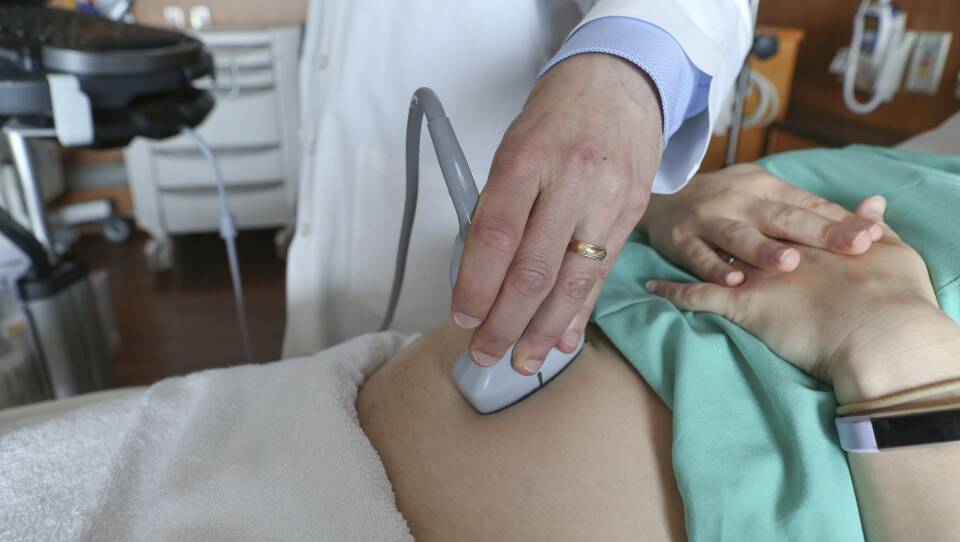 A health care worker uses an ultrasound machine to scan a patient's abdomen.