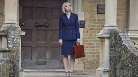 Trixie stands in front of Nonnatus in a sharp suit