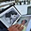 A man's hand rests atop two photos of a woman that he has in a folder. One is black-and-white photo of a young woman and a color photo of an old woman.