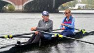 Two rowers maneuver in the rain toward a bridge.