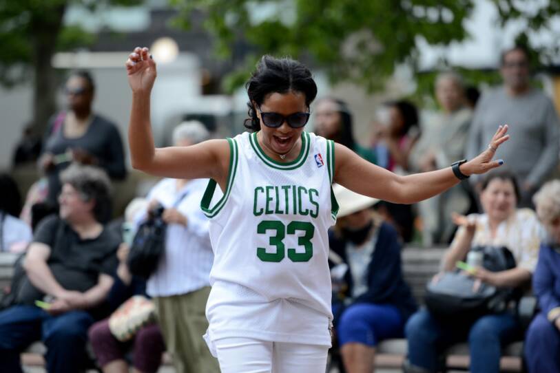 A woman in a Boston Celtics jersey dances outside.