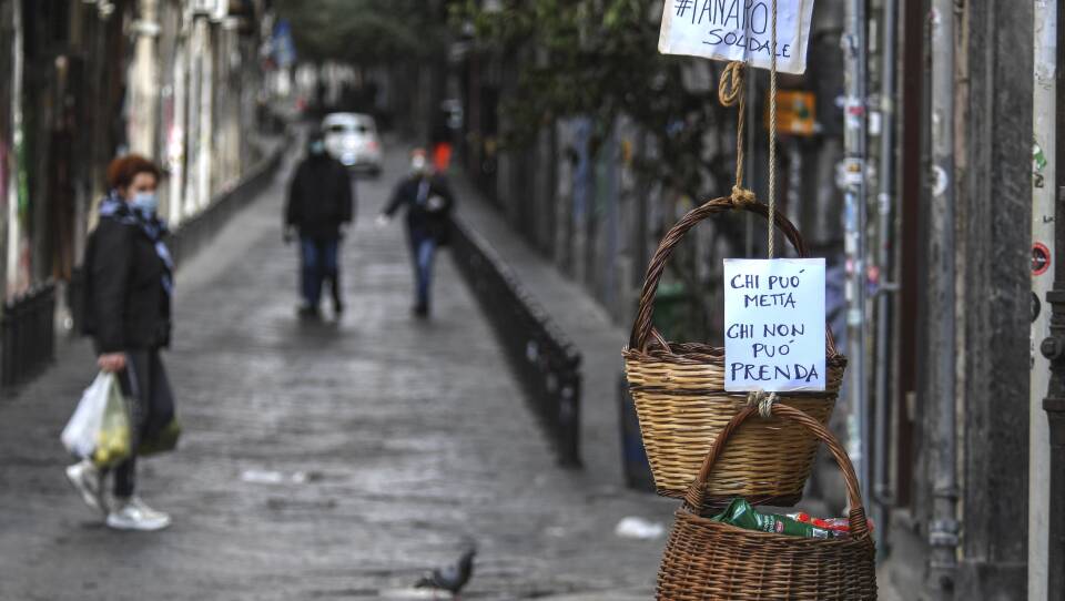A solidarity basket with a note reading "Those who can, put something in, those who can't, help yourself" is hung in the historic center of Naples.