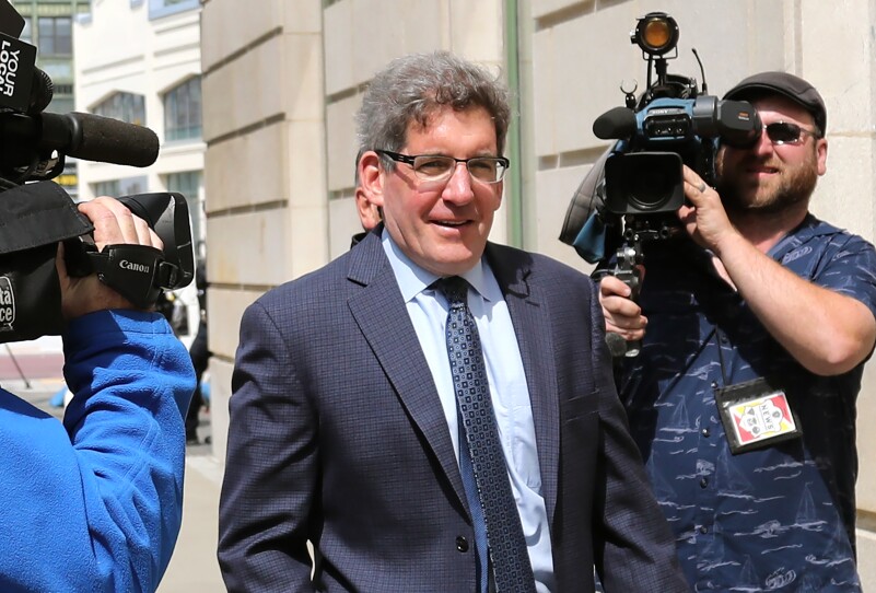 A man in a suit walks past TV cameras