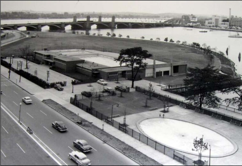 A black and white aerial photo of a three-lane highway and a pool complex.