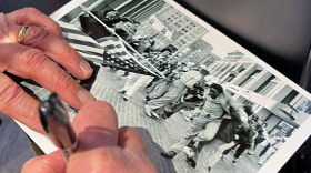 A hand signs a photo in Sharpie.