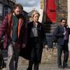 DCI Jess James (Sinéad Keenan) and DI Sunny Khan (Sanjeev Bhaskar) walk Marty Baines (Maximilian Fairley) to a squad car.