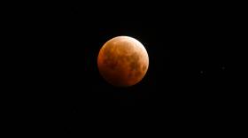 Light shines from a total lunar eclipse over Santa Monica Beach, Calif., in May 2021.