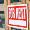 Closeup of red, white for rent sign attached, hanging on wooden apartment, house, home, building door with glass windows