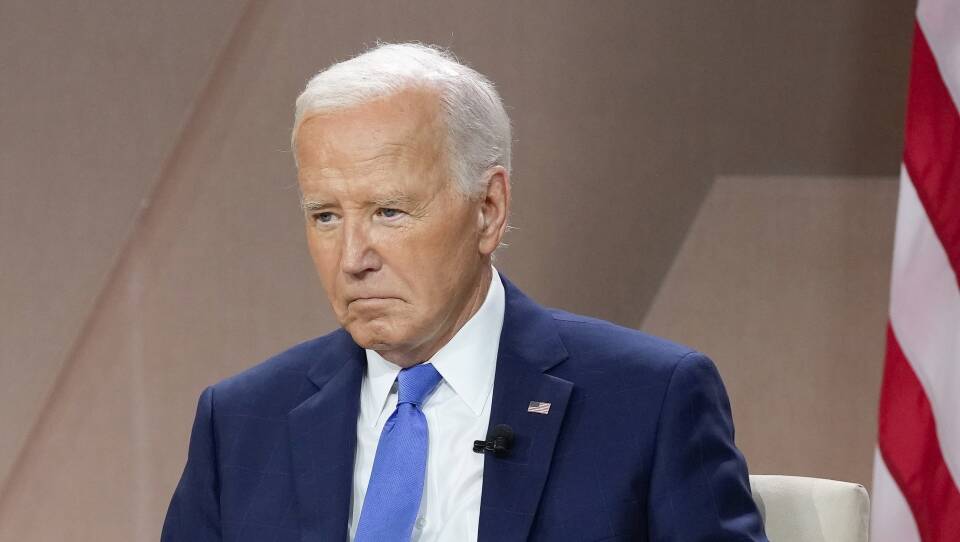 Biden looks somber while seated in a suit.