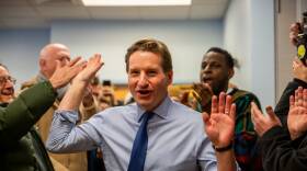 Dean Phillips walks through a crowd of people, hands raised as he high-fives people on both sides.