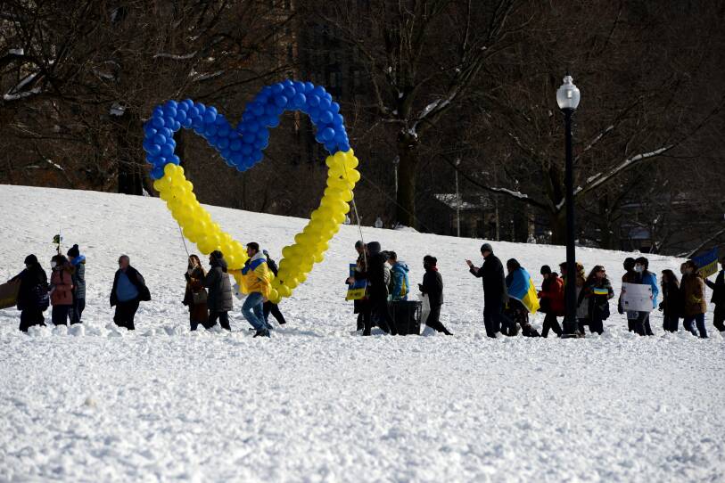 A long line of people make their way along a path in the snow.