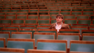 Jesus Molina sits in a theater, surrounded by empty chairs.