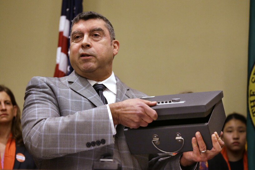 A man holds up a gun lock box.