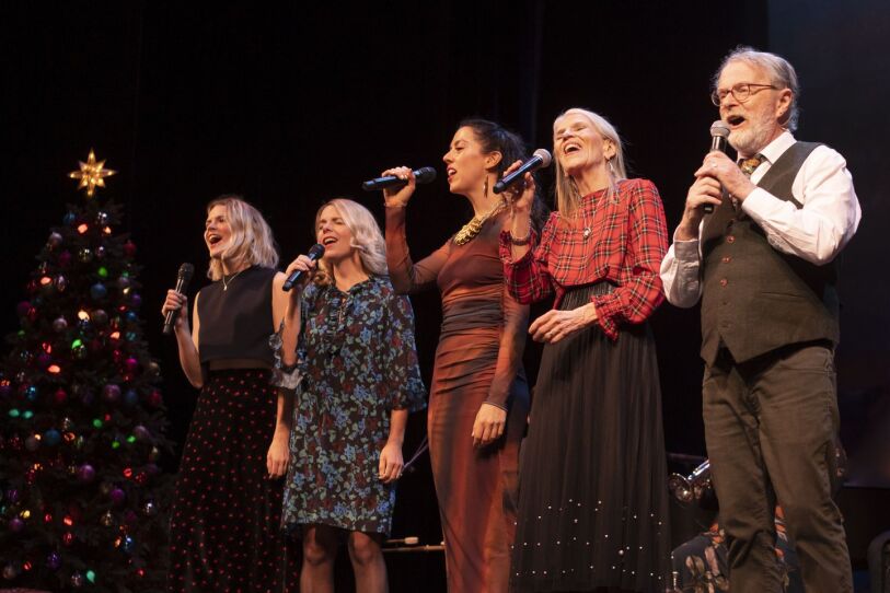 This photograph is from the December 18, 2022 production of "A Christmas Celtic Sojourn." Five people are on stage, singing. to their left is a Christmas tree. From left to right we see the following performers: Nuala O'Donovan, Aoife O'Donovan, Lily Henley, Lindsay O'Donovan, Brian O'Donovan