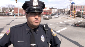 A police officer stands at the side of a large intersection.