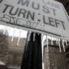 Icicles hanging off a sign that says "left lane must turn left."