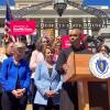 Ayanna Pressley stands at a podium with the Massachusetts seal on it. Other elected officials and people holding signs that say "Abortion is Health Care" are behind her.