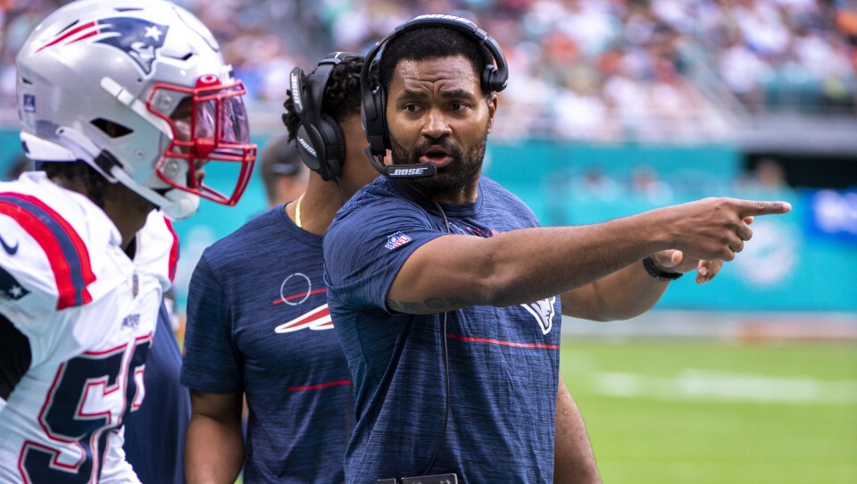 A man wearing a heatset points, looking intently at a Patriots player