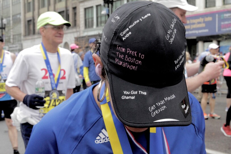 Close-up on a black hat with different messages written on it: "From Pre-K to the Boston Marathon!" "Corre mucho y fuerte" "Get that Medal"