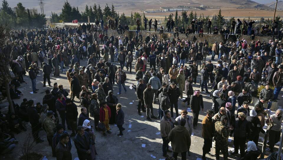 A group of people stand in a dirt field.