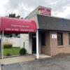 A small, single-story building with a red awning covering the sidewalk by the door that reads "pregnancy services, walk-ins 508-507-8378"