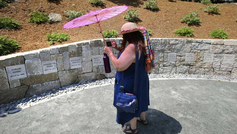 Karla Hailer, a teacher from Scituate, Mass., takes a video on July 19, 2017, where a memorial stands at the site in Salem, Mass., where five women were hanged as witches more than three centuries years earlier. Massachusetts lawmakers on have formally exonerated Elizabeth Johnson Jr., clearing her name 329 years after she was convicted of witchcraft at the height of the Salem Witch Trials.