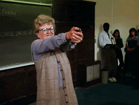 A woman fires a prop gun, revealing a flag that reads "bang!"