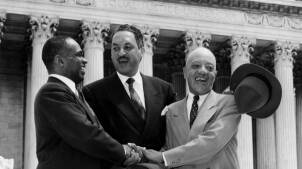 Three Black lawyers hold hands and smile as they stand on the steps of the U.S. Supreme Court.