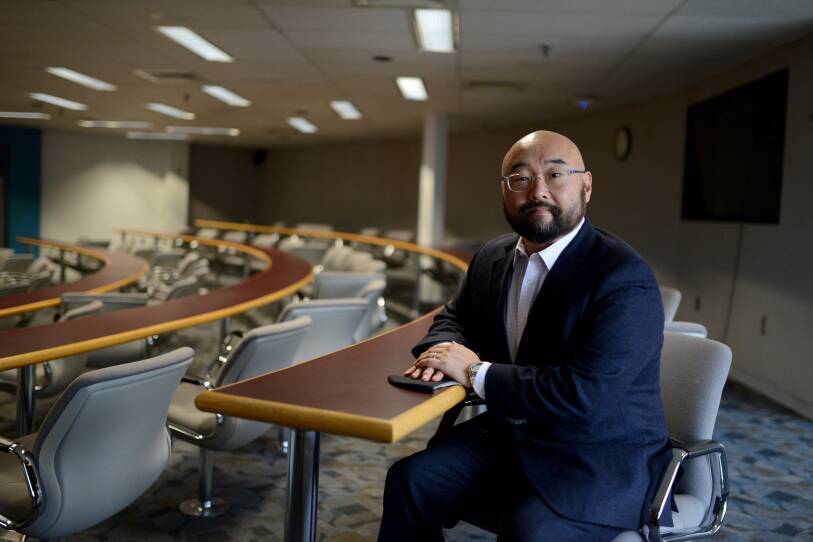 A man sitting at a desk in a lecture hall.