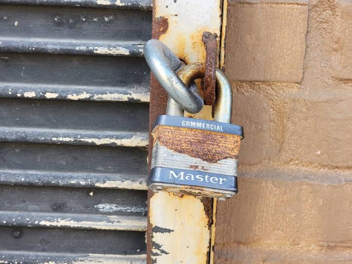 A rusted Master padlock clips two metal loops together