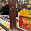 A man behind a movie theater concession counter serves a customer checking out at the register.