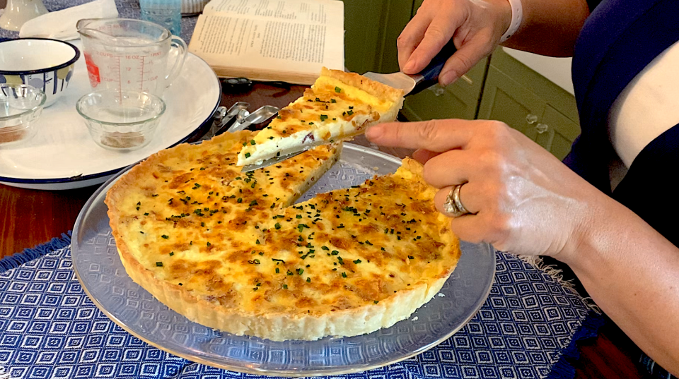 A woman holds up a slice of Quiche Lorraine