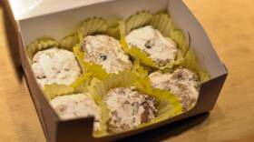 A box shoes six cookies coated in powdered sugar.