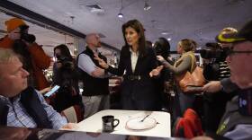 Nikki Haley stands by a table in a small diner, speaking to two men eating breakfast.