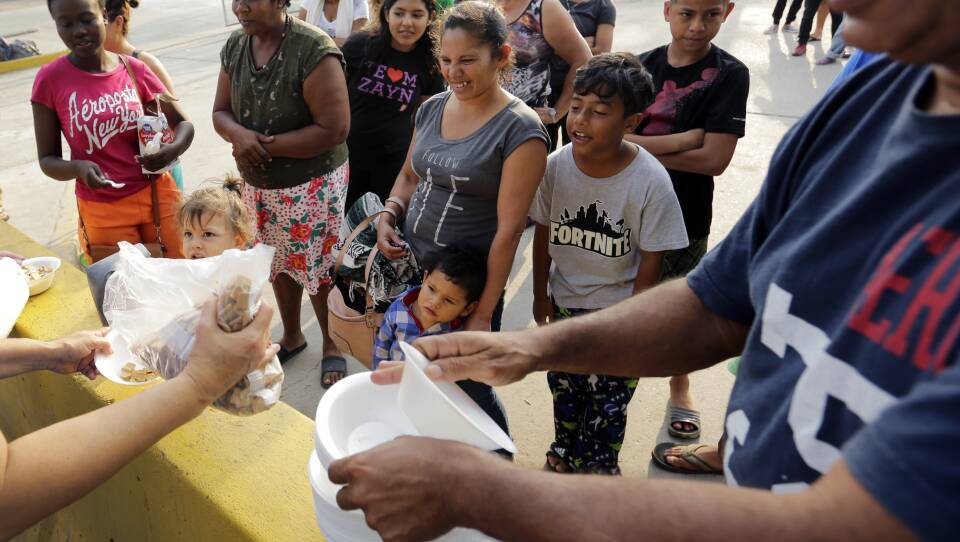Migrants seeking asylum in the United States receive breakfast from a group of volunteers near the international bridge in Matamoros, Mexico.