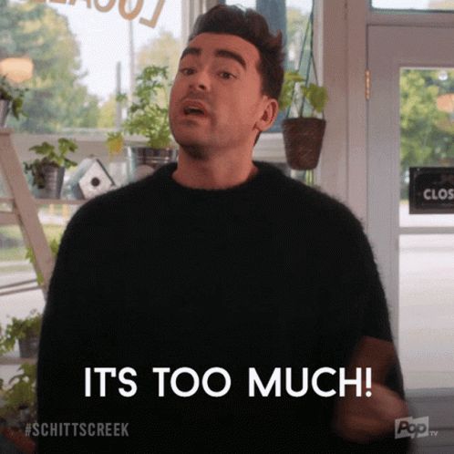 Daniel Levy as David Rose in Schitt's Creek says "It's Too much!" David is a tall man with black hair and thick black eyebrows. He wears a black sweater and shakes his finger to emphasize his statement.