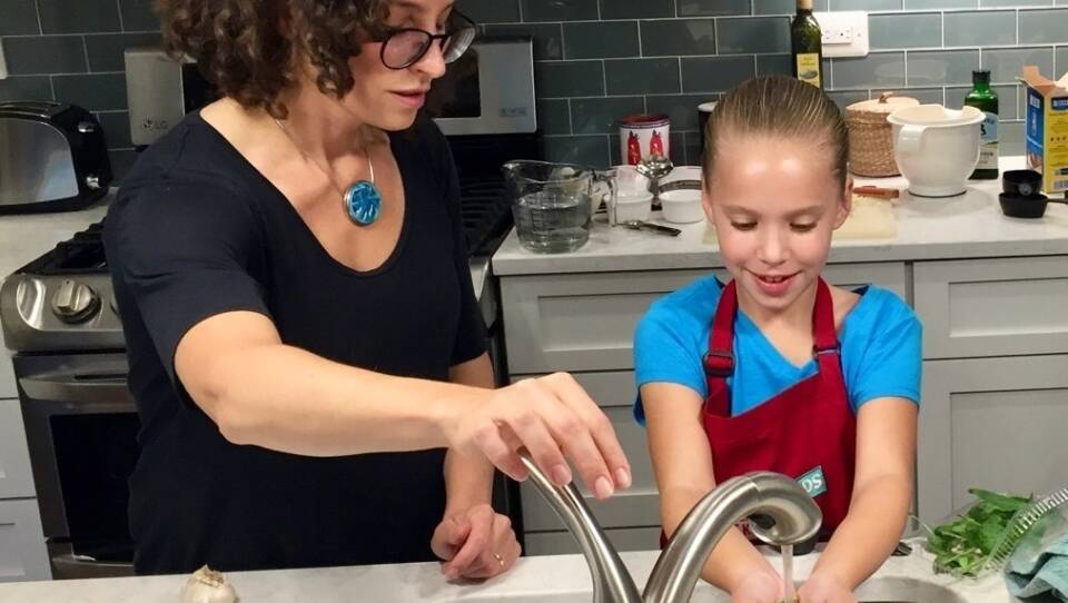 Molly Birnbaum, America's Test Kitchen Kids editor in chief, helps 8-year-old Lucy Gray make a one-pot pasta meal from a recipe in the new book, The Complete Cookbook for Young Chefs.