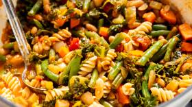 Soup bowl full of pasta, kale, carrot chunks, green beans, cannelloni, and other vegetables