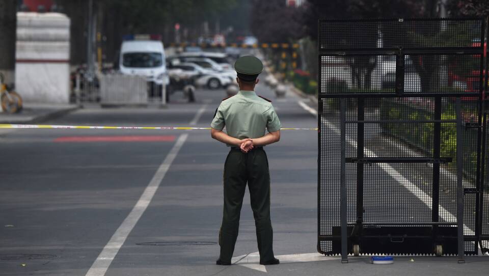 A law enforcement officer stands guard at the entrance of the Xinfadi market Saturday in Beijing. A fresh cluster of coronavirus cases linked to the market prompted officials to institute immediate and sweeping restrictions, including the market's closure.