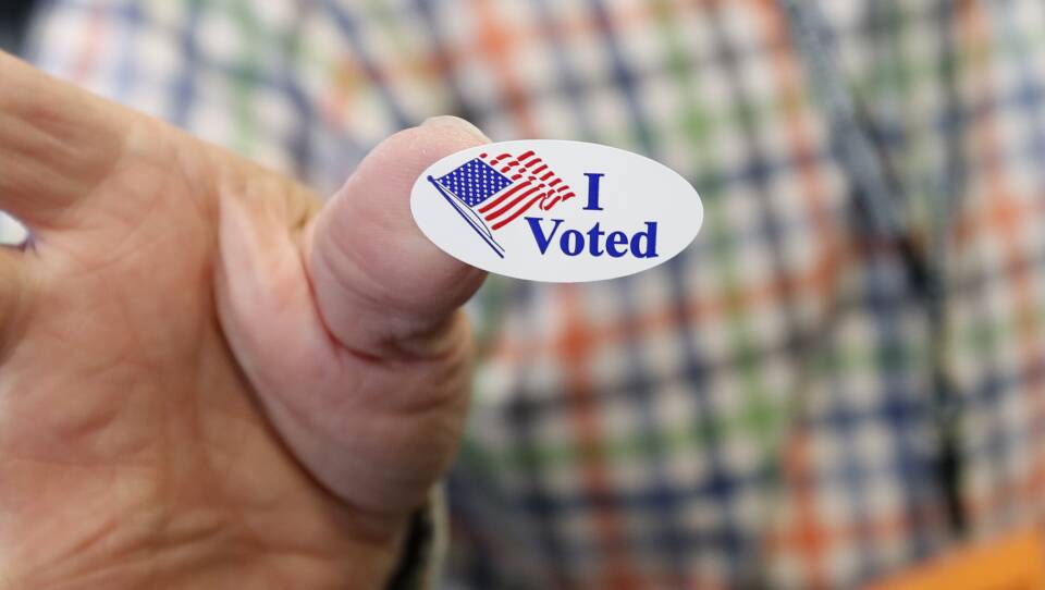 Cliff Smith, a Ridgeland, Miss., poll worker, offered an "I Voted" sticker in Jackson, Miss., on Election Day in 2019.