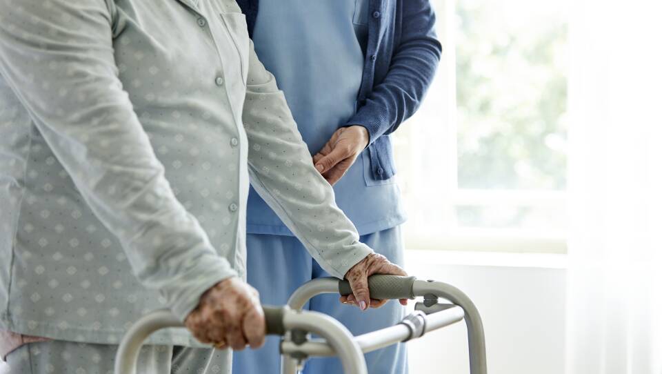 Nurse supporting disabled elderly woman in walking