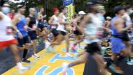 Dozens of people run so fast they appear blurry as they cross a large "START" banner painted on the street beneath their feet.