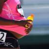 A pregnant woman in running gear, with a Gatorade bottle in one hand and her hand on her belly in the other.