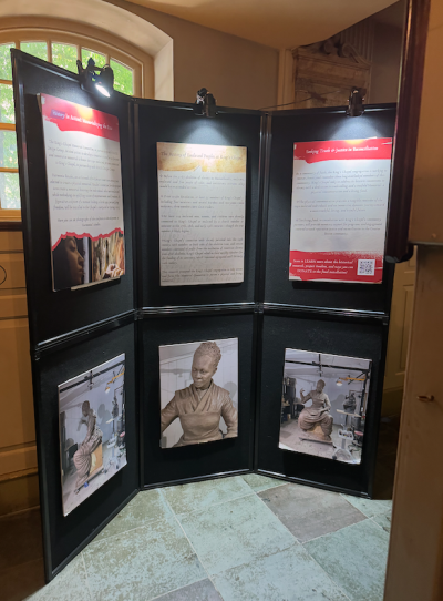 A display board has text about slavery and photos of a state of a woman.