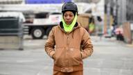 A female construction worker stands in front of a construction site.
