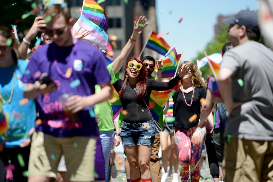 A group of people waving rainbow flags at Boston Pride parade