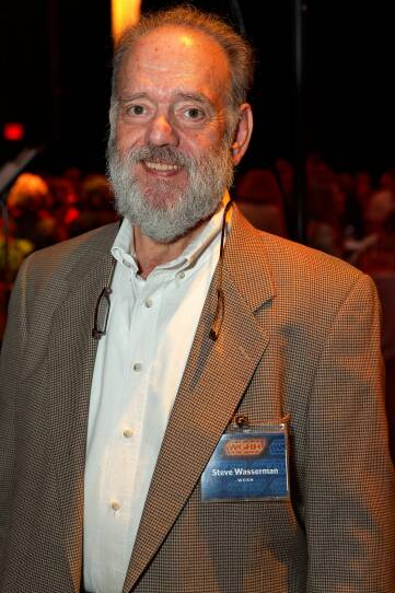 An older man wears a tweed jacket and a nametag that says "Steve Wasserman"