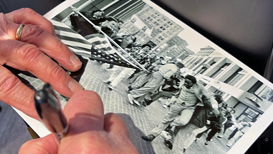 A hand signs a photo in Sharpie.