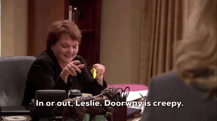 A woman says "In or out, Leslie. Doorway is creepy."